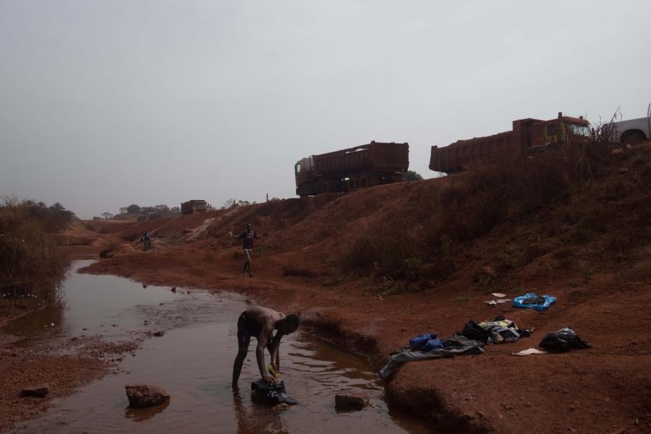 Man Washing Clothes Near Bauxite Mining