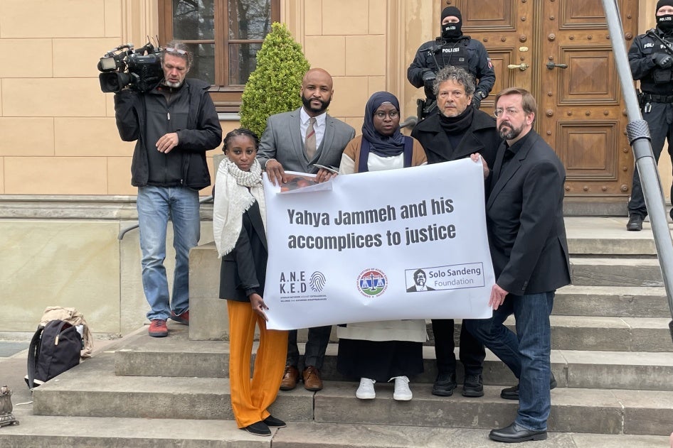 A group of people standing on steps hold a sign