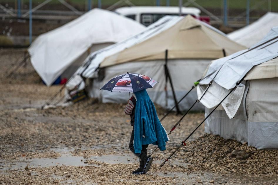 Un jeune tient un parapluie alors qu'il marche sous la pluie au Camp Roj, où sont détenus des proches de personnes soupçonnées d'appartenir au groupe État islamique (EI), dans le nord-est de la province de Hasakah, en Syrie, le 4 mars 2021.