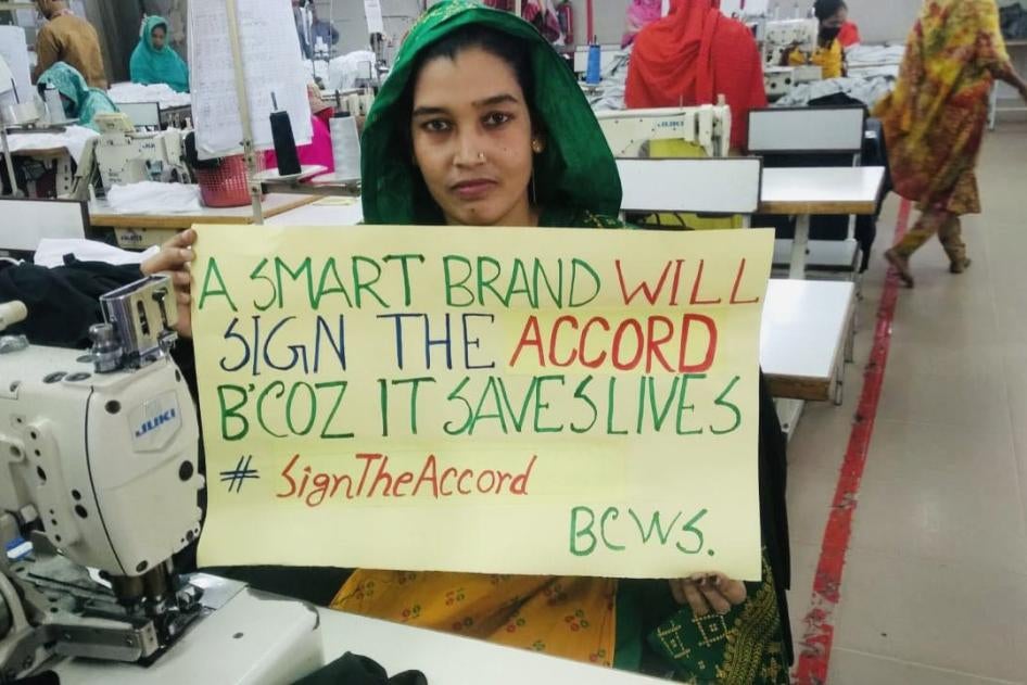 A garment factory worker in Bangladesh holds a sign to stand up for safe factories and the International Health and Safety Accord