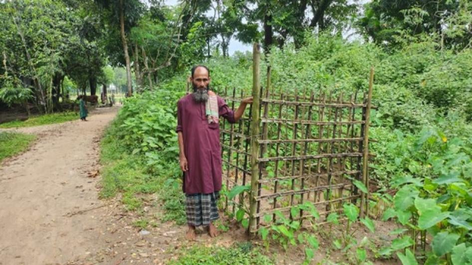 A man stands next to a gravesite