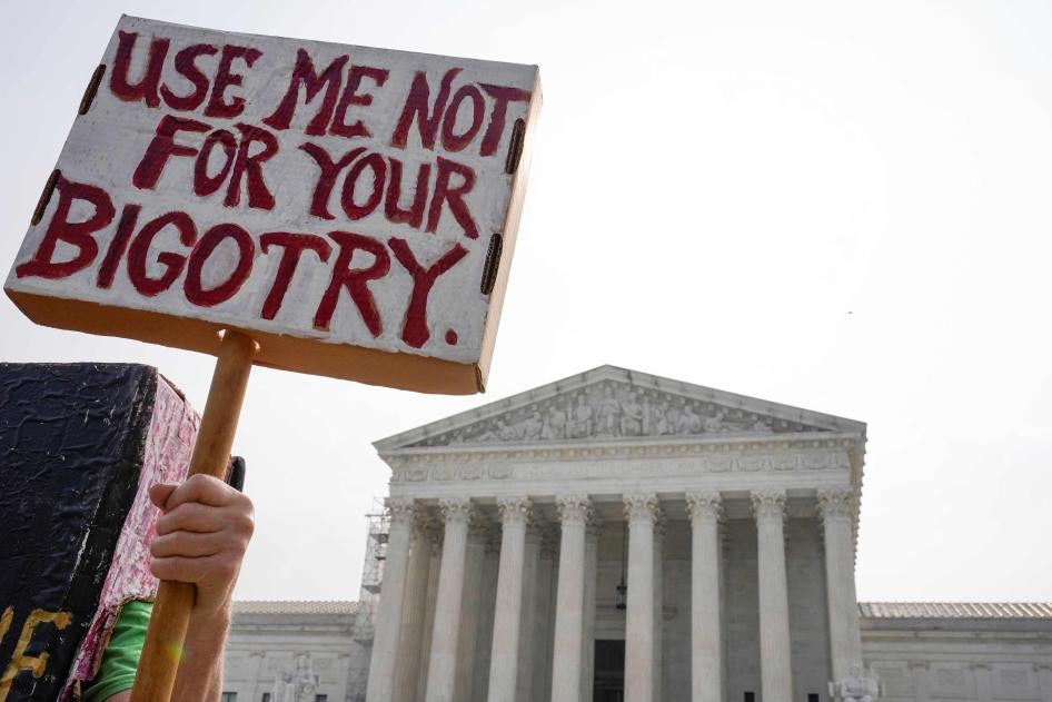 A person holds a protest sign that says "Use Me Not For Your Bigotry"