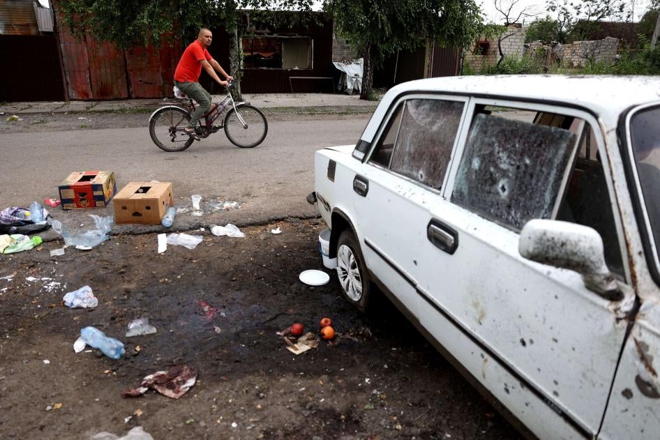 A man rides past a place where a woman was killed by a Russian cluster munition strike in Lyman, Donetsk region, Ukraine on July 8, 2023. 