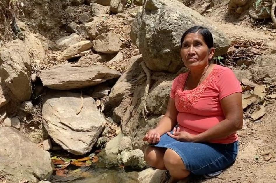 A woman sits next to a small pool of water