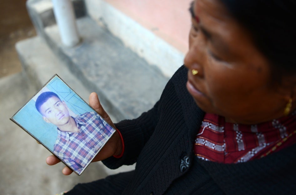 A woman displays a photograph of her son