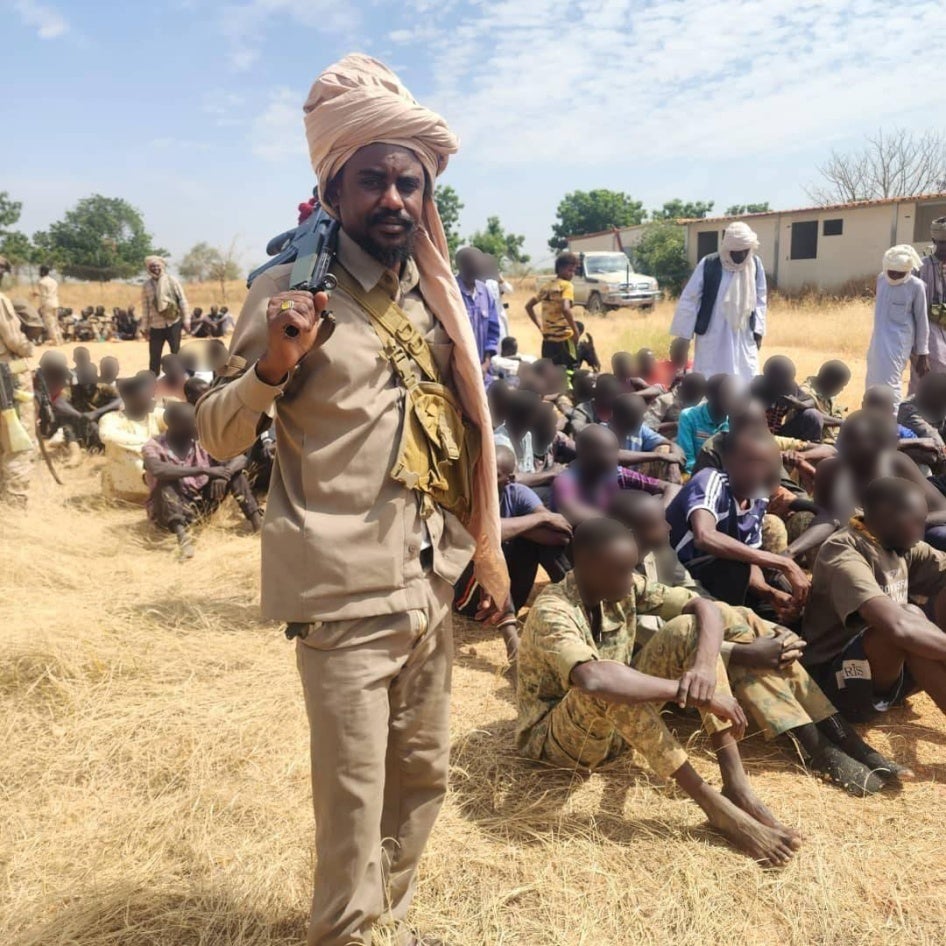 Fighters stand over a group of men seated on the ground