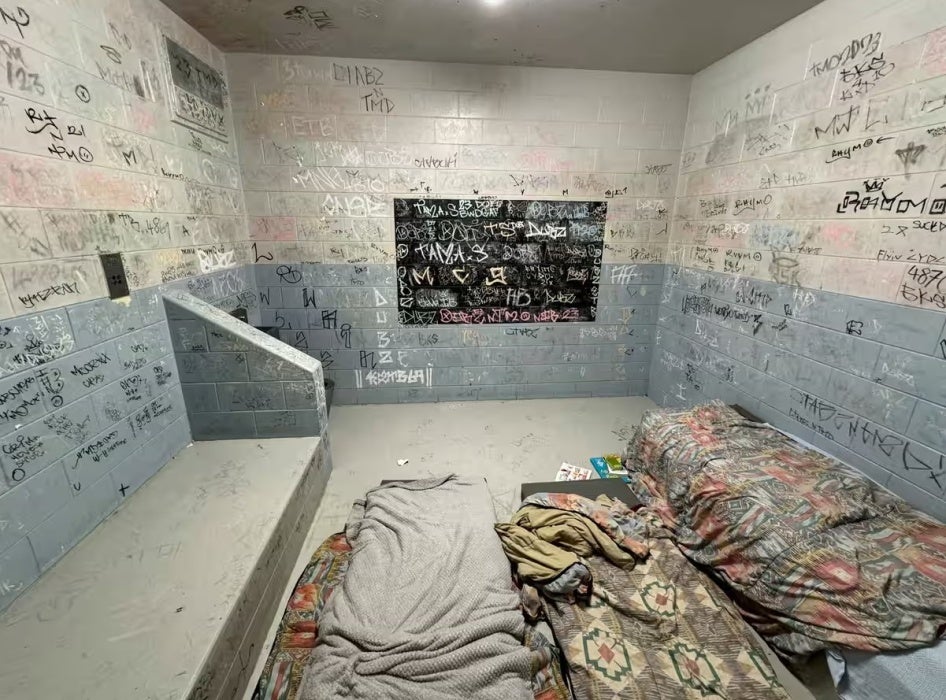 A detention cell with writing on its walls.