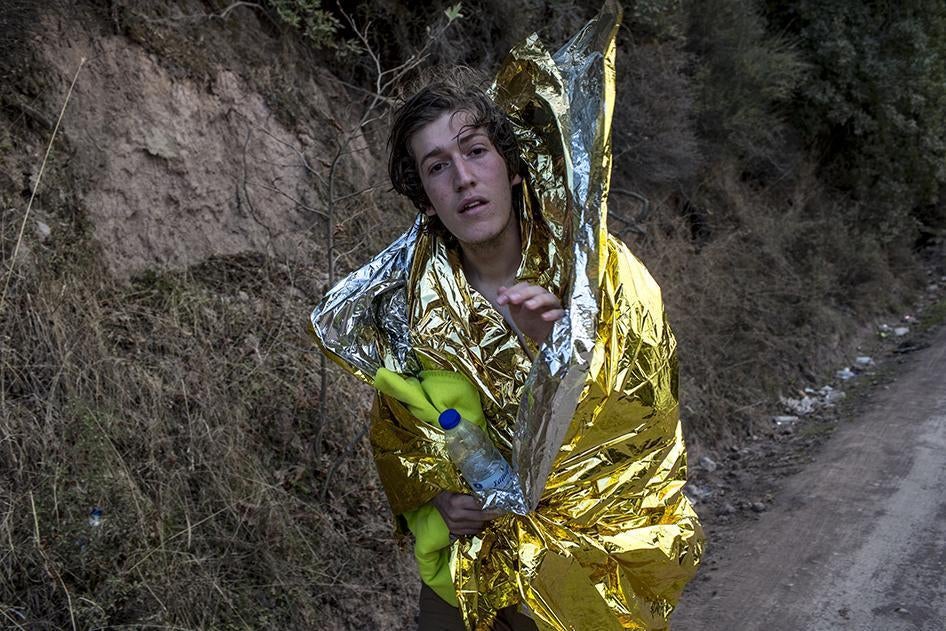 Ο Ali, ένας 17χρονος αφγανός αιτών άσυλο στέκεται τυλιγμένος με μια θερμική κουβέρτα επιβίωσης στην ακτή της Λέσβου, έχοντας διασωθεί από μια υπερφορτωμένη φουσκωτή λέμβο που δέχθηκε επίθεση από κουκουλοφόρους ένστολους άνδρες, οι οποίοι αφαίρεσαν τον κιν