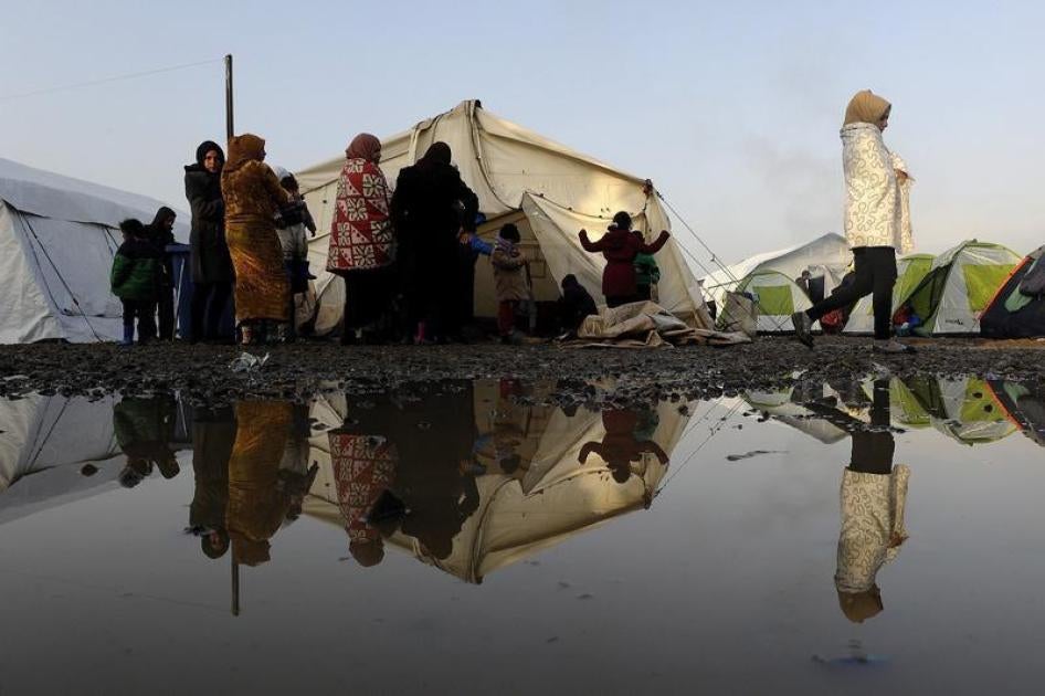 Stranded refugees and migrants walk inside a relocation camp as they wait to cross the Greek-Macedonian border, near the Greek village of Idomeni, March 1, 2016.