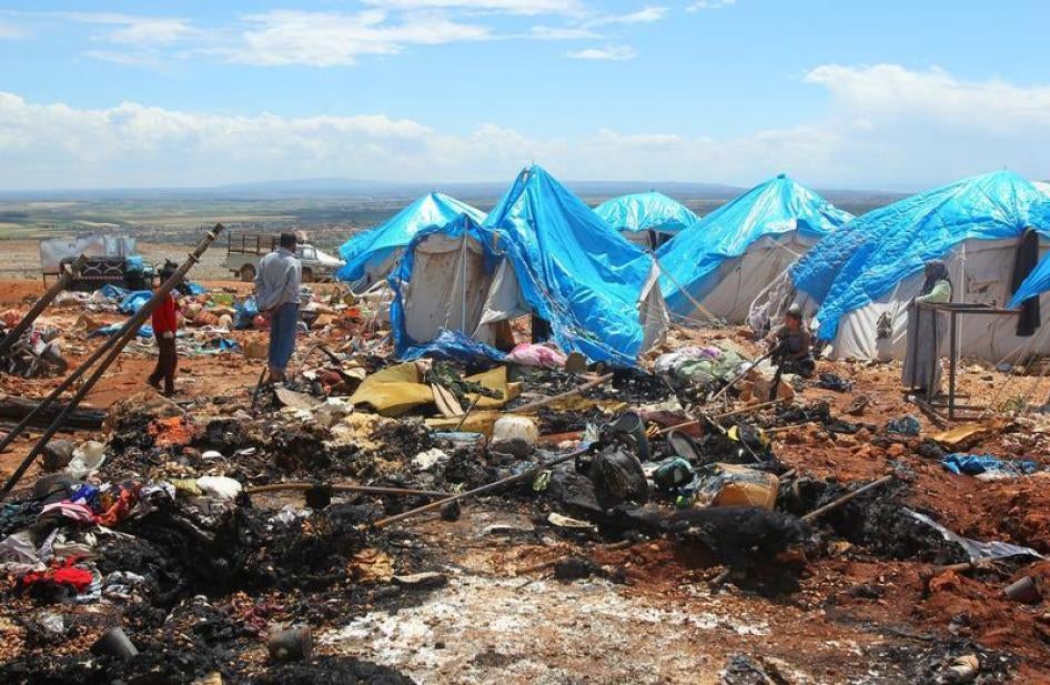 People stand near the damage after air strikes on May 5 hit a camp for internally displaced people in Syria's Idlib province near the Turkish border, May 7, 2016.