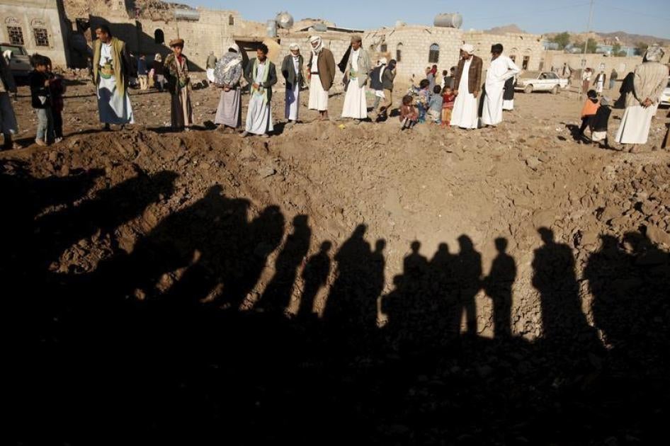 People stand around a crater caused by a Saudi-led air strike on the outskirts of Yemen's capital Sanaa, December 29, 2015. 