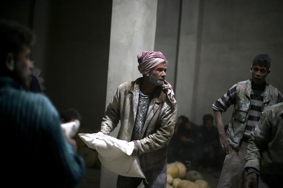 Un homme syrien tient un sac de farine distribué par le Croissant-Rouge dans la ville de Jesreen en Ghouta orientale, le 7 mars 2016, alors que l’acheminement d’aide humanitaire à d’autres zones était toujours bloqué.