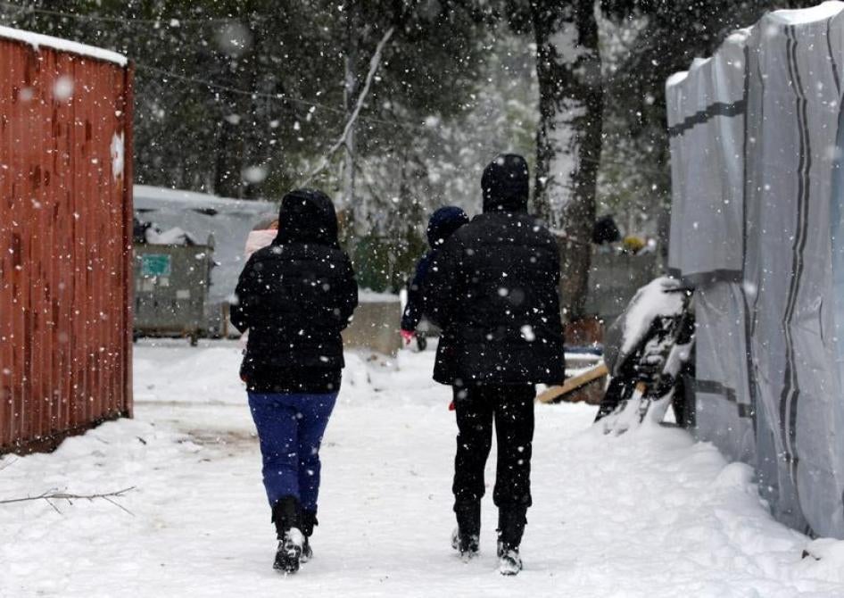 Stranded Syrian refugees carry their children through a show storm at a refugee camp north of Athens, Greece January 10, 2017.
