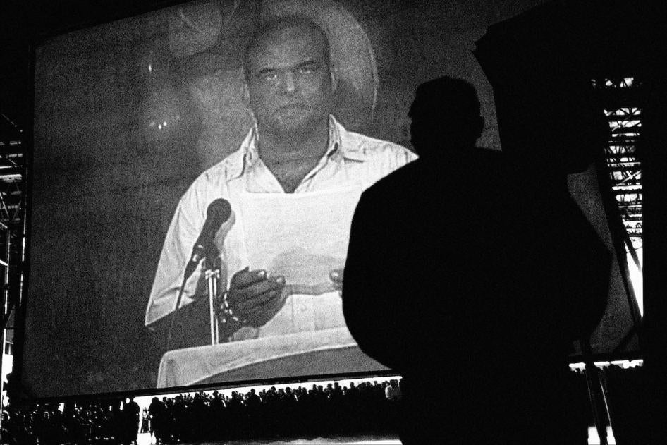 Paramilitary leader Salvatore Mancuso addresses paramilitary troops on a video screen during the demobilization ceremony of the Cacique Nutibara Block of the United Self-Defense Forces of Colombia, Medellín, November 25, 2003. 