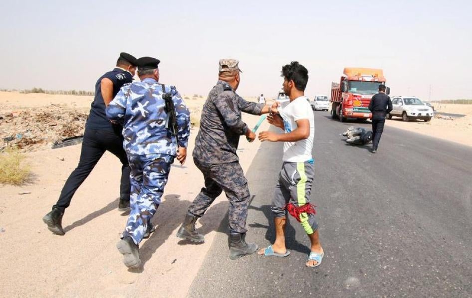 An Iraqi security officer grabs a protester during a demonstration at al-Burjisiya oil field near Basra City, Iraq, July 17, 2018. © 2018 Essam al-Sudani/Reuters