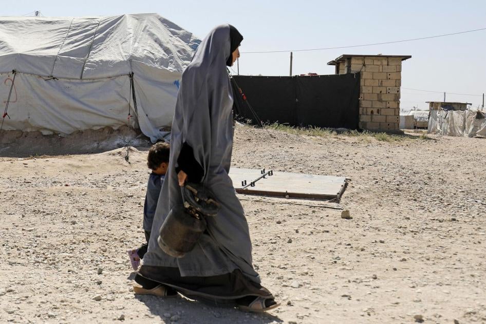 Une femme marche avec un enfant dans le camp de Roj, où sont détenus des épouses et des enfants étrangers de membres de l'État islamique (EI, ou Daech), dans le nord-est de la Syrie, en septembre 2018.  © 2018 Delil Souleiman/AFP/Getty Images