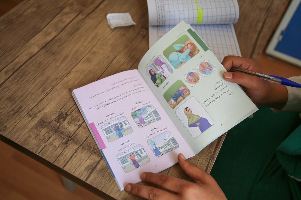 A woman holds open an illustrated guidebook on reproductive health