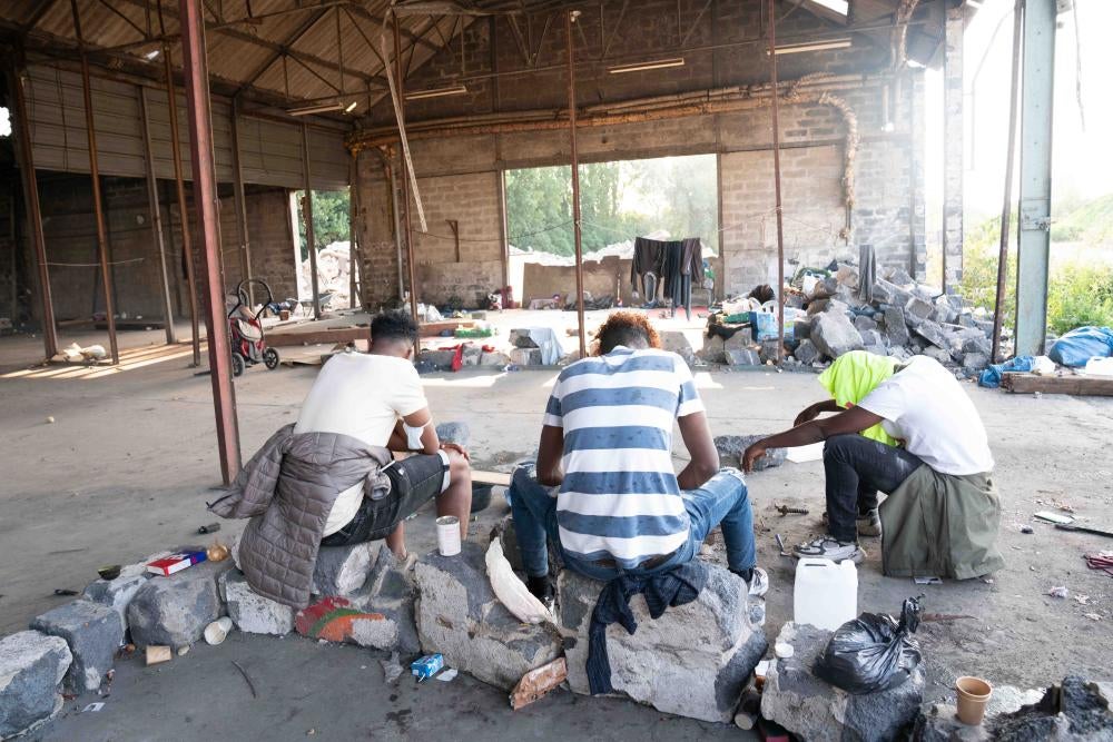 Three boys sit in an abandoned warehouse