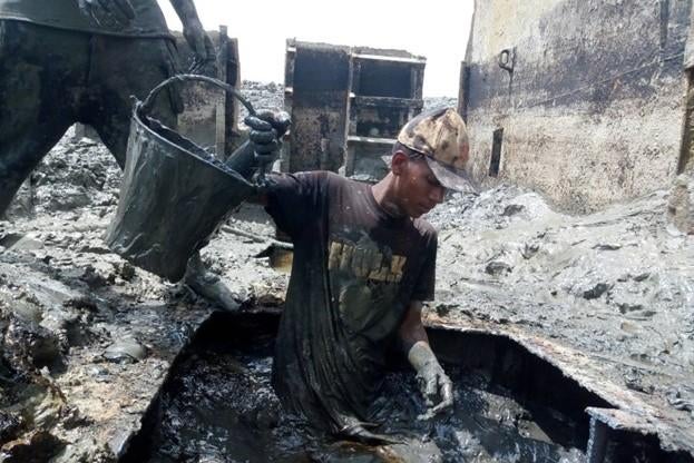 Shipbreaking workers clearing sludge from a ship. 