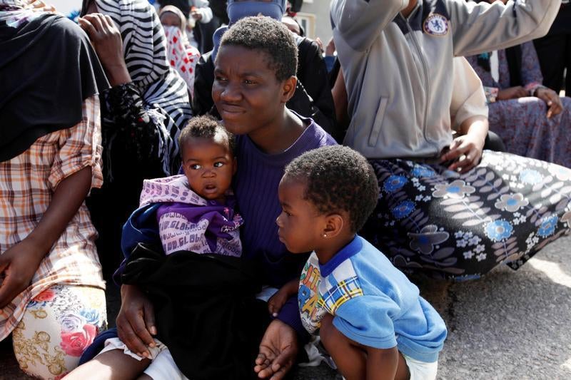 A man sits with his children during a visit by U.N. Special Representative and Head of the United Nations Support Mission in Libya, Martin Kobler, and International Organization for Migration, Director General William Lacy Swing, at a detention camp in Tr