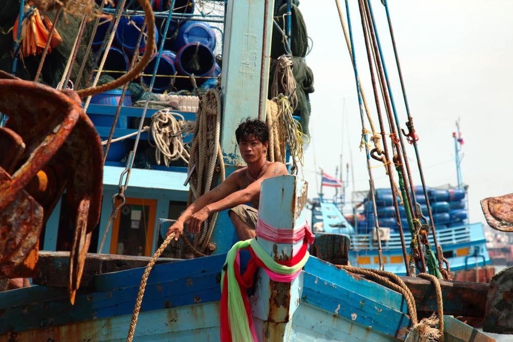 A fisher at the prow of a boat, mooring rope in hand, as the vessel arrives in port in Pattani, August 12, 2016.