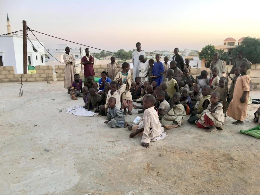 A group of talibé children on the rooftop terrace of a daara in Touba, Senegal that housed over 100 talibés in a large, unfinished building with no paved floors. At night, the children either slept inside on sheets on the sand, or on the terrace, exposed 