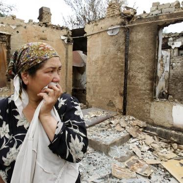 An ethnic Uzbek woman reacts as she stands at her house burnt down during clashes in the city of Osh, June 24, 2010.