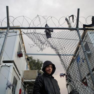 A boy stands next to a hole in the fence of the Moria camp following rainfall, on the island of Lesbos, Greece, November 22, 2019. 