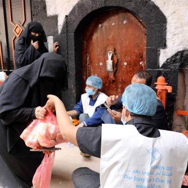 An aid worker gives a food ration to a woman in Sanaa, Yemen, July 19, 2020