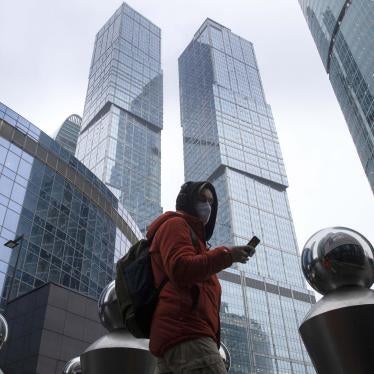 A man wearing a face mask to protect against Covid-19 uses his smartphone among Moscow City skyscrapers in Moscow, Russia, January 11, 2021.