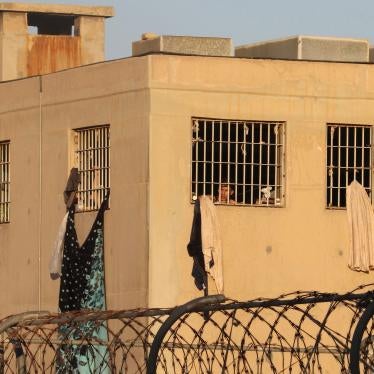 A man looks out from behind the bars of a prison building