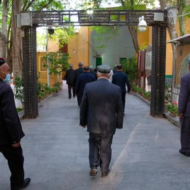 Uyghur Muslims walk under an arch with security cameras after prayers at the Id Kah Mosque in Kashgar in China's Xinjiang region, during a government-organized trip for foreign journalists, April 19, 2021.