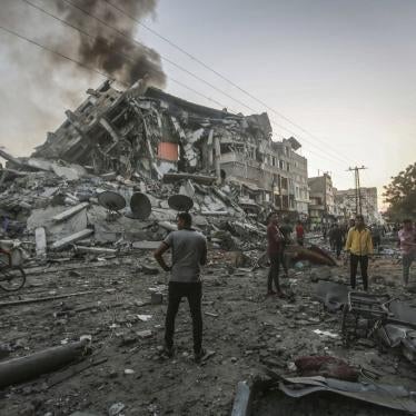 People in the Gaza Strip stand near the site of the collapsed al-Shorouk tower