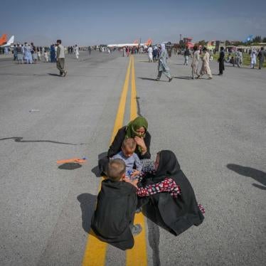 Several Afghans sit on the tarmac awaiting to leave from Kabul's airport on August 16, 2021.