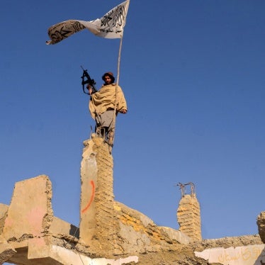 A Taliban fighter raises a flag in the ruins of Sangin, Helmand province, Afghanistan, November 30, 2021.