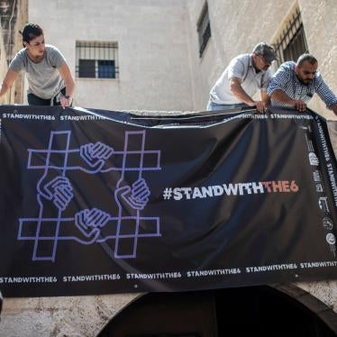 نشطاء يعلّقون لافتة تضامنا مع منظمات مجتمع مدني فلسطينية محظورة على مقر إحداها، منظمة "الحق" لحقوق الإنسان، في 18 أغسطس/آب 2022.