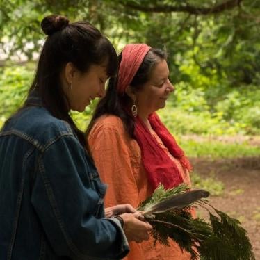 Two women stand together in the woods
