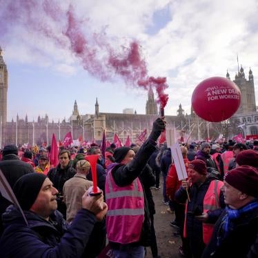 A large crowd holding signs and chanting slogans gathers in the UK