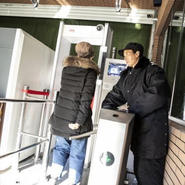 A Chinese security officer watches a woman pass through a checkpoint, equipped with a metal detector and facial recognition technology, to enter the main bazaar in Urumqi in the Xinjiang region of China.