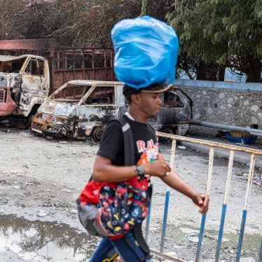 A man walks past several torched cars