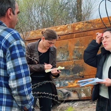 Two women take notes and interview a man outside