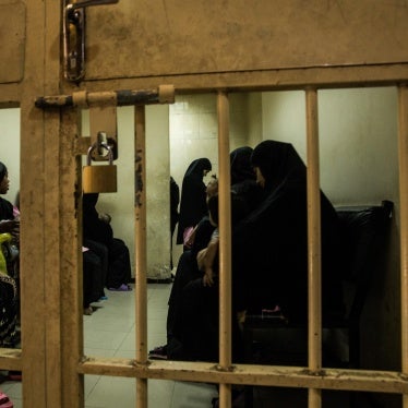 Women and children wait in a holding cell