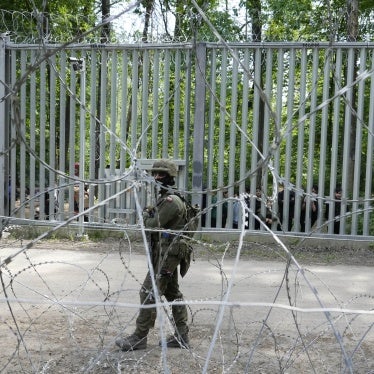 A Polish soldier patrols the metal barrier border with Belarus, in Bialowieza Forest, with migrants stranded on the Belarusian side, May 29, 2024.