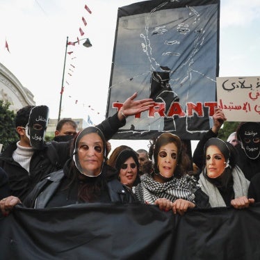 Demonstrators hold up a banner bearing the effigy of Tunisian President Kais Saied that reads ''Tyrant,'' while others wear masks representing Tunisian women jailed or detained by the authorities including Bensedrine , during a protest in Tunis, January 14, 2025. 