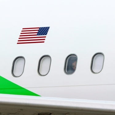 Migrants look out the windows of a plane