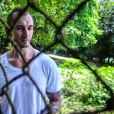 A man poses for a photo behind a fence