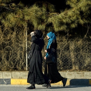Afghan women walk past razor barricades along a roadside in Kabul on December 8, 2024.