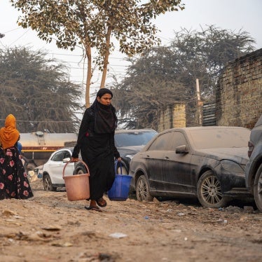 A Rohingya woman carries drinking water in Madanpur Khadar refugee camp, India, January 14, 2024.