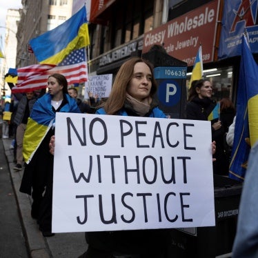 A demonstrator holds a sign that reads "No Peace Without Justice" at a protest