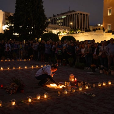 A woman lights a candle for the victims of the Tempi railway collision that killed 57 people in February 2023, as people gather in front of the Greek Parliament to support the hunger strike of Panos Routsi, the father of a boy killed in the collision, in Athens on September 28, 2025.